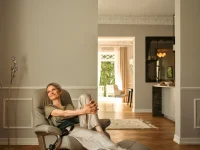 Woman smiling in Stressless Sunrise recliner with smoked oak ottoman